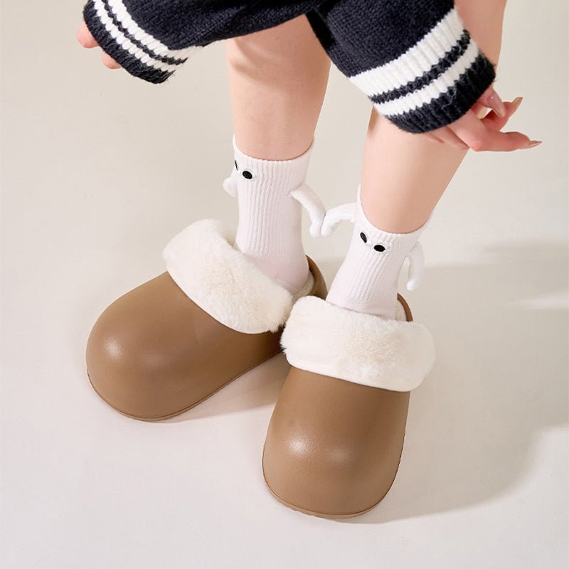 Chaussons douillets Doudounea pour enfant en marron avec bordure fourrée blanche, portés avec des chaussettes mignonnes à motifs, confort intérieur optimal