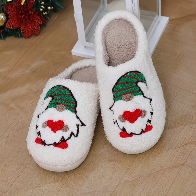 Chaussons de Noël Doudounea blancs douillets avec motif lutin vert et rouge, intérieur en peluche beige, parfaits pour l'hiver festif