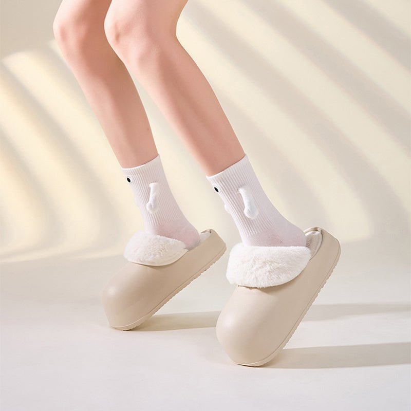 Chaussons d'intérieur Doudounea beige avec bordure en fausse fourrure blanche, portés avec des chaussettes blanches motif lapin, style minimaliste